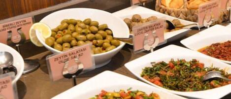 A buffet with various dishes including olives, salads, and bread.