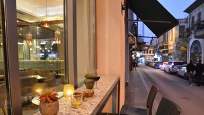 An outdoor bar area with seating, a view of the street, and a glass railing. - Waxwing Hotel (Antakya)