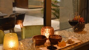 A table with a glass of red wine, a candle, and a bowl of nuts. - Waxwing Hotel (Antakya)