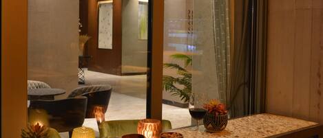 Un vestíbulo de hotel con una recepción, zona de estar y un espejo grande que refleja el interior.