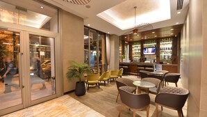 A modern bar area with seating, a television, and a bar stocked with bottles. - Waxwing Hotel (Antakya)
