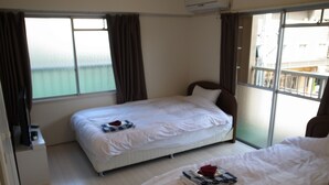 Habitación de hotel con dos camas, una ventana con cortinas, un equipo de aire acondicionado y vista al mar.