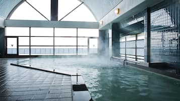 A large indoor swimming pool with a high ceiling and large windows.