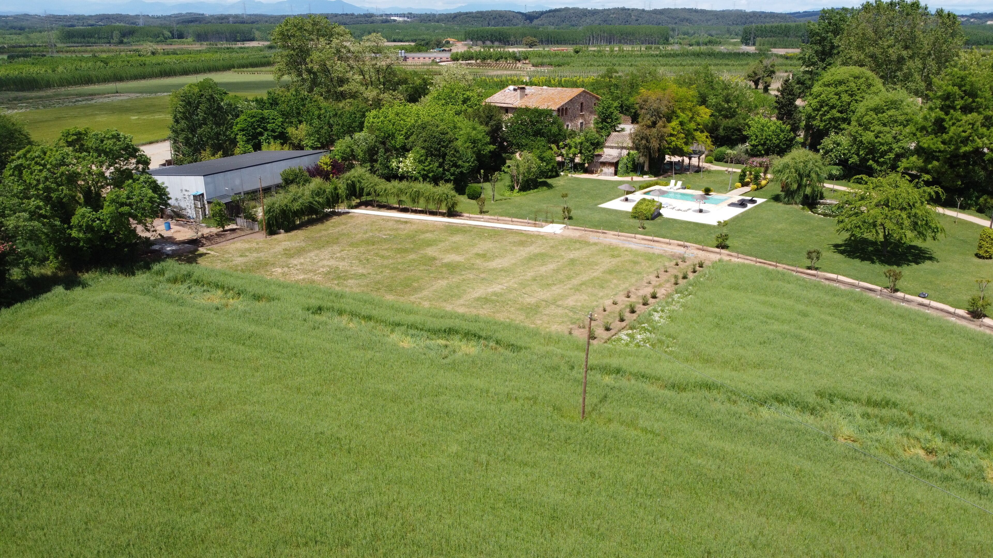 Il s’agit d’une propriété rurale dotée d’un grand champ verdoyant, d’une piscine et de plusieurs bâtiments, dont une maison et des dépendances.