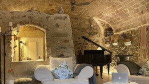 A cozy room with a piano, a laptop, and a sofa with decorative pillows.