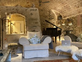 Una habitación acogedora con un piano, una computadora portátil y un sofá con cojines decorativos.