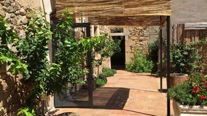 A stone building with a covered patio area, a stone wall, and a tiled pathway.
