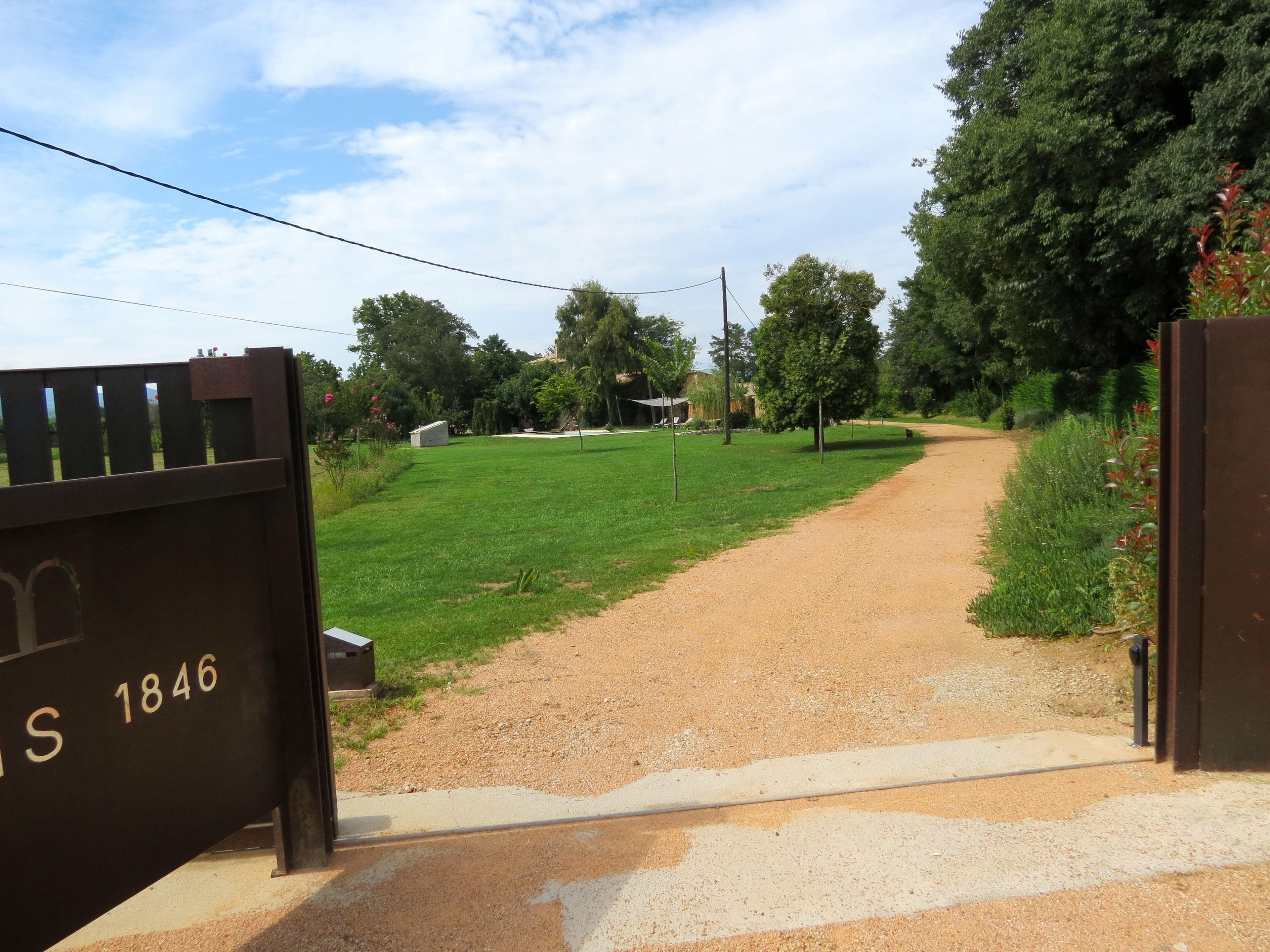 A gravel path leading through a grassy area with trees and a gate labeled "S 1846".