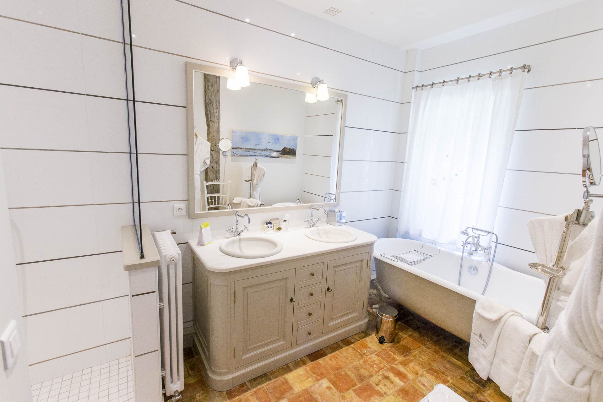 Un baño moderno con dos lavamanos, un espejo grande, una bañera y una ventana con cortina.