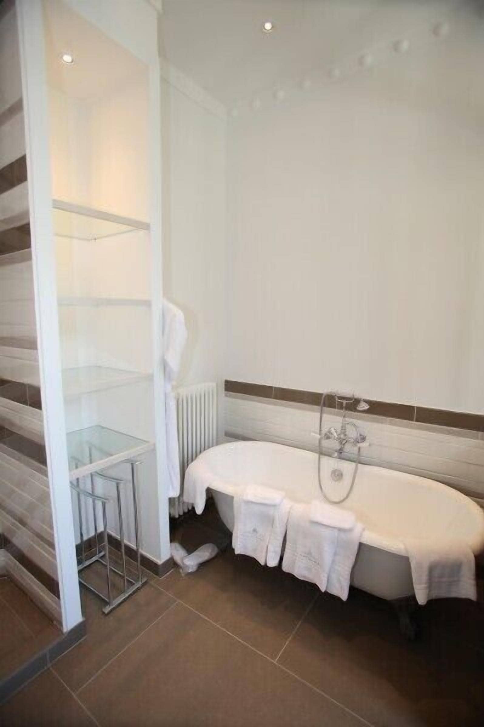 A bathroom with a bathtub, a glass shower enclosure, and a white towel rack.