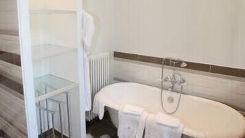 A bathroom with a bathtub, a glass shower enclosure, and a white towel rack.
