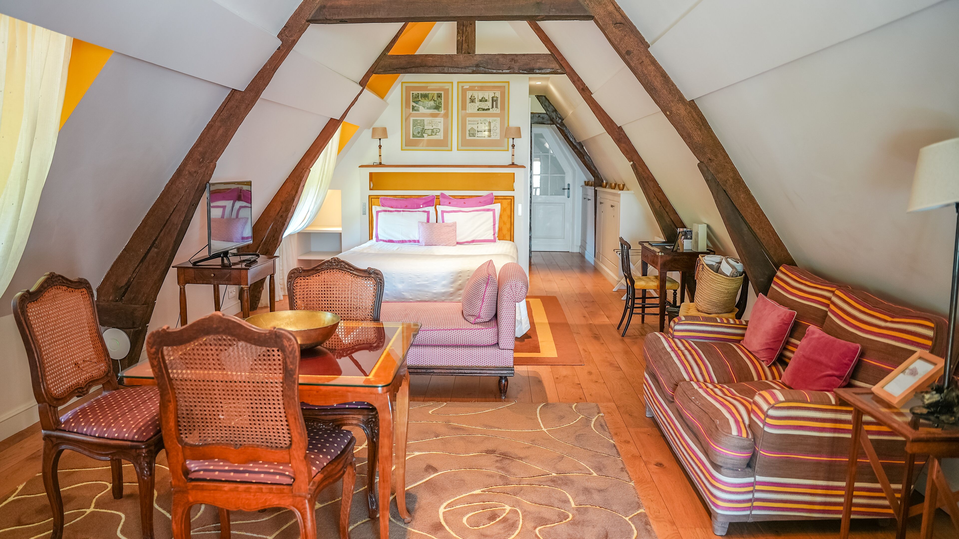 Une chambre confortable située dans les combles, avec un lit, un canapé et un coin repas.