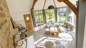 A spacious room with a large window, a sofa, a table, and a chair. - Le Clos de Grâce (Honfleur)