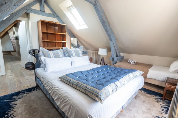 Un dormitorio con una cama grande, una estantería de madera y un techo inclinado con tragaluces.