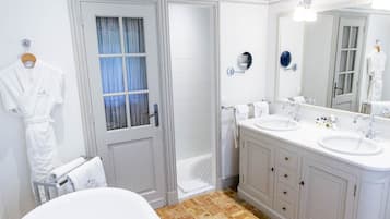 Une salle de bain spacieuse dotée d’une grande baignoire, d’un meuble-lavabo à deux vasques et d’une douche à l’italienne.