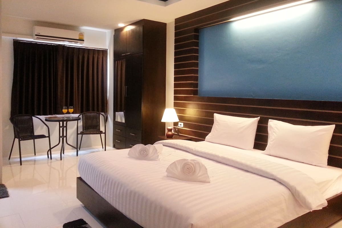 A hotel room with a large bed, a desk with two chairs, a lamp, and a view of the city.