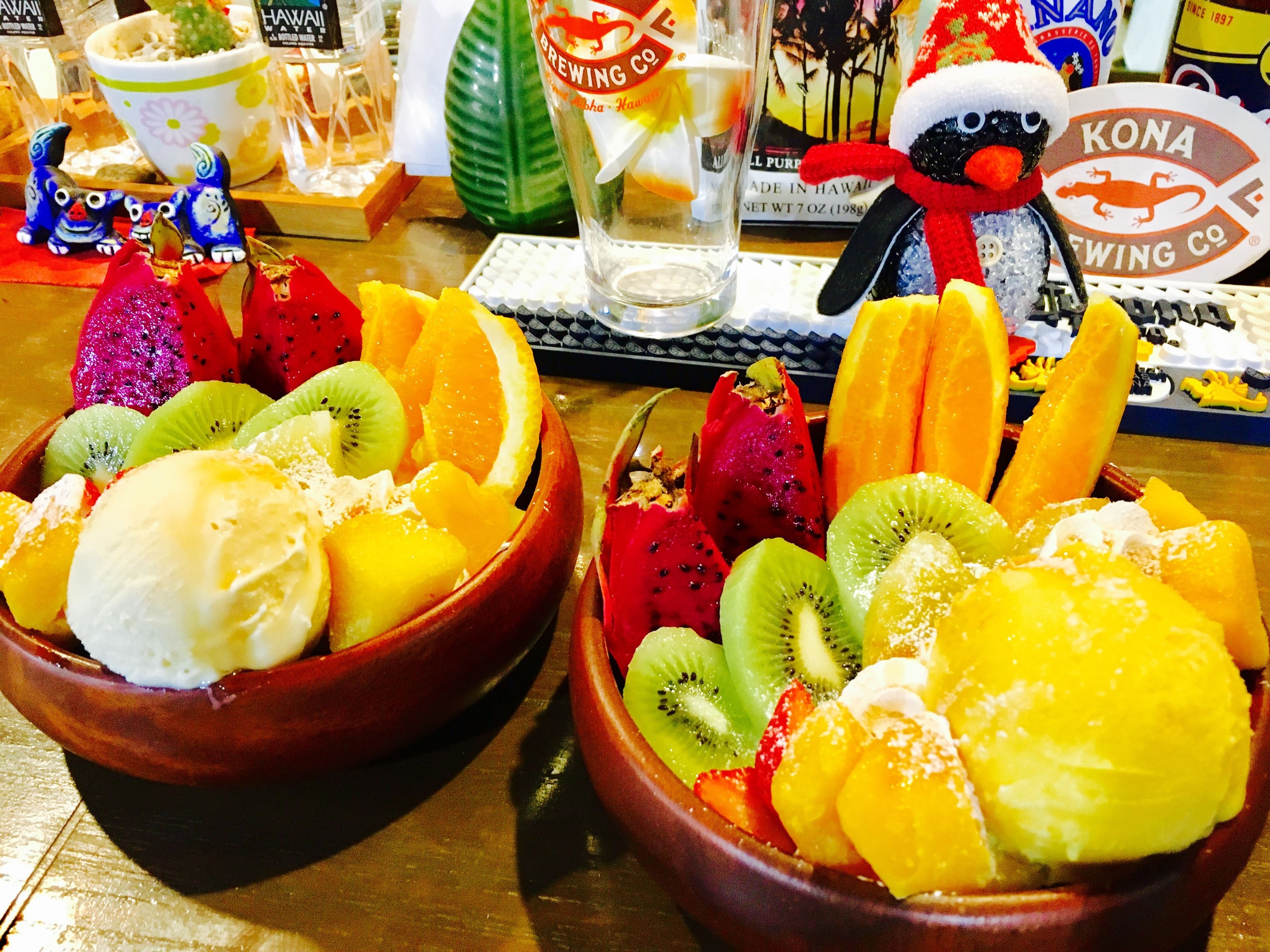 Zwei Schalen Obst und Eis auf einem Tisch, im Hintergrund sind verschiedene Gegenstände zu sehen.