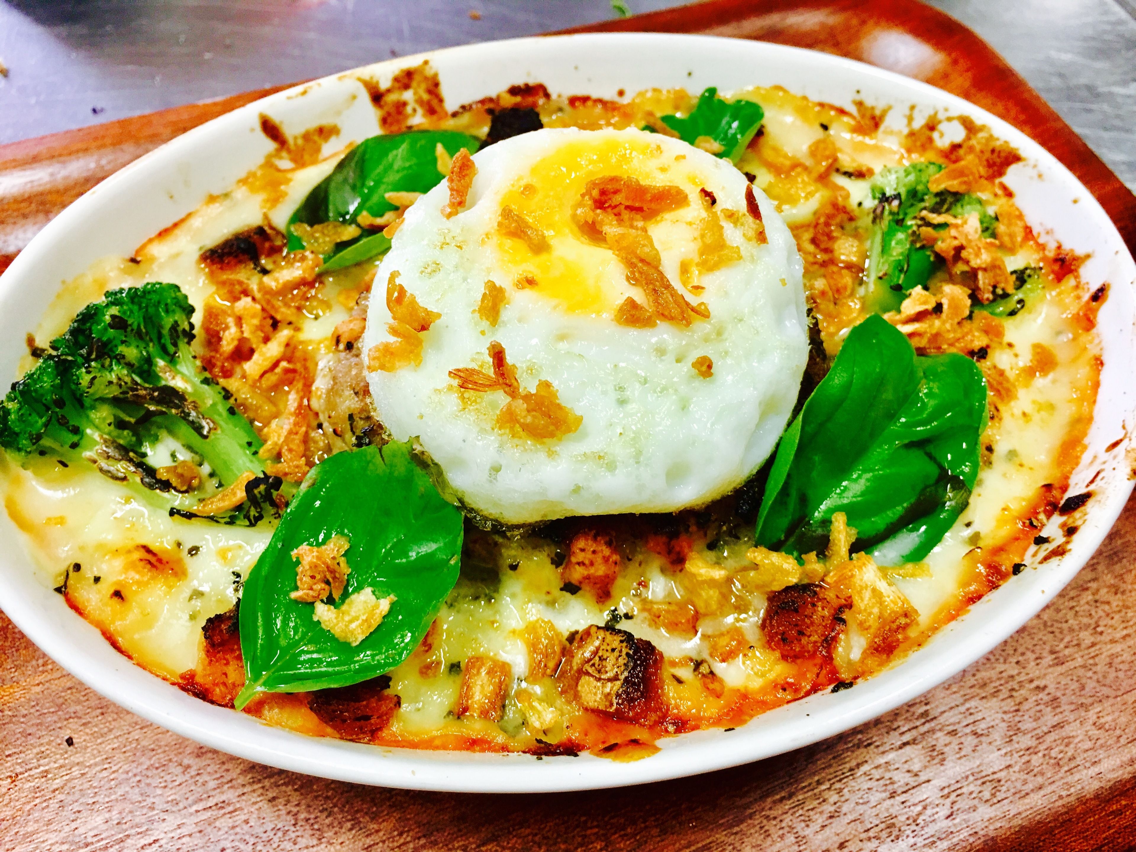 A dish with a fried egg, broccoli, and cheese.