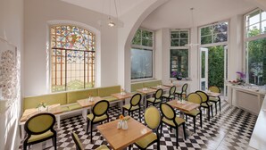 Een restaurant met een geruite vloer, groene zittingen en grote ramen met een glas-in-lood ontwerp.