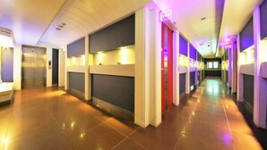 A hotel corridor with a modern design, featuring a central walkway, walls with built-in shelves, and a ceiling with recessed lighting. - Sense Motel (Busan)