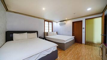 A bedroom with two beds, a wooden floor, a window, and an air conditioning unit.