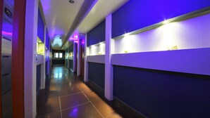 A hotel hallway with blue walls, white trim, and a tiled floor. - Sense Motel (Busan)