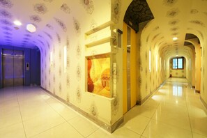 Un largo pasillo bien iluminado con diseños ornamentales en las paredes y piso de baldosas.
