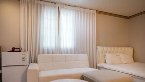 A hotel room with a sofa, a bed, a small table, and a refrigerator. - Sense Motel (Busan)