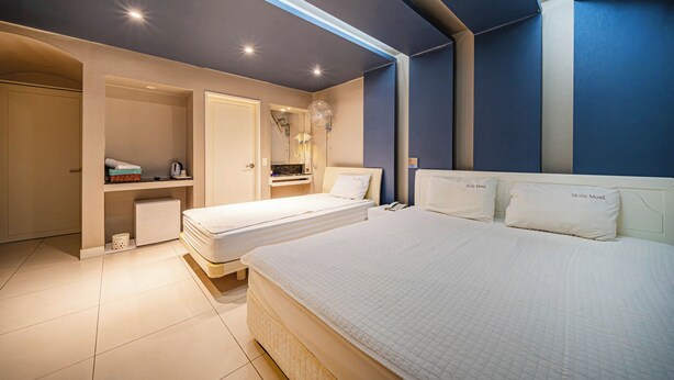 A bedroom with two single beds, a small desk, and a wardrobe. - Sense Motel (Busan)