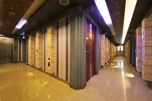 Un pasillo con piso pulido, columnas verticales y paredes decoradas con banderines verticales.