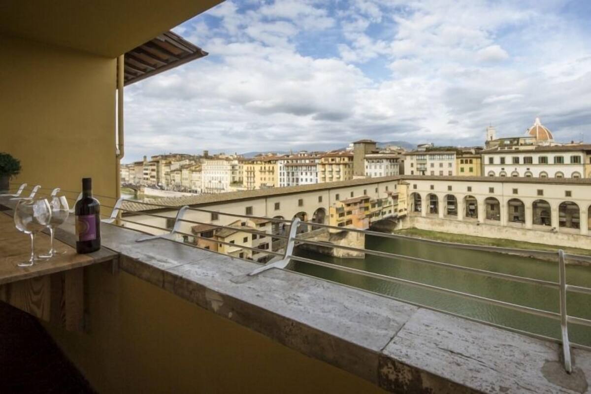 A balcony with a view of a river, historic buildings, and a bridge.
