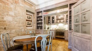 A stone-walled dining area with a wooden table and chairs, a kitchen with cabinets, and a tiled backsplash. - Florentapartments - Ponte Vecchio (Florence)