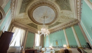 A room with a large chandelier, a bed, a desk, and a window with curtains. - Florentapartments - Ponte Vecchio (Florence)