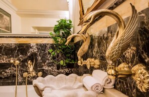 A luxurious bathroom with a marble sink, ornate gold fixtures, and a decorative plant. - Florentapartments - Ponte Vecchio (Florence)