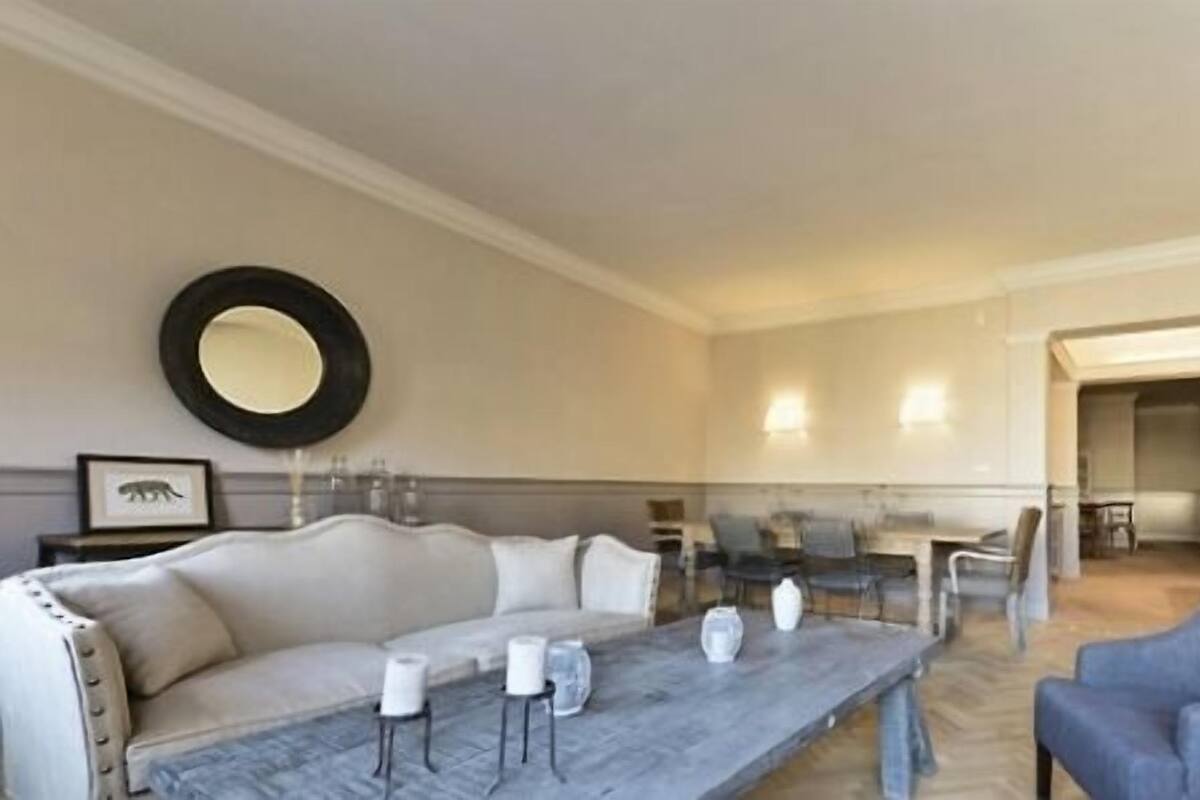 A spacious living room with a sofa, armchairs, a coffee table, and a dining area.