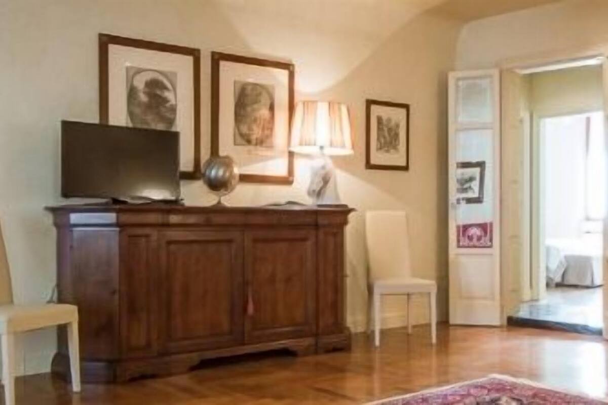 A spacious living room with a wooden cabinet, a television, and a red sofa.