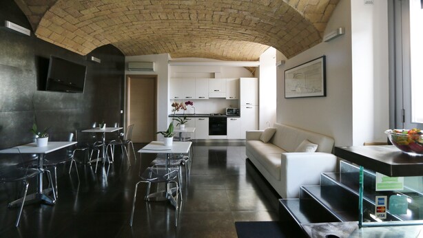 A modern interior with a dining area, kitchen, and seating space. - Residenza Adriana (Rome)