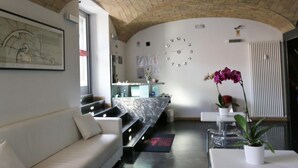A modern living room with a curved ceiling, a sofa, a coffee table, and a potted orchid. - Residenza Adriana (Rome)