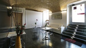A modern lobby with a brick ceiling, a white sofa, a glass table, and a staircase. - Residenza Adriana (Rome)