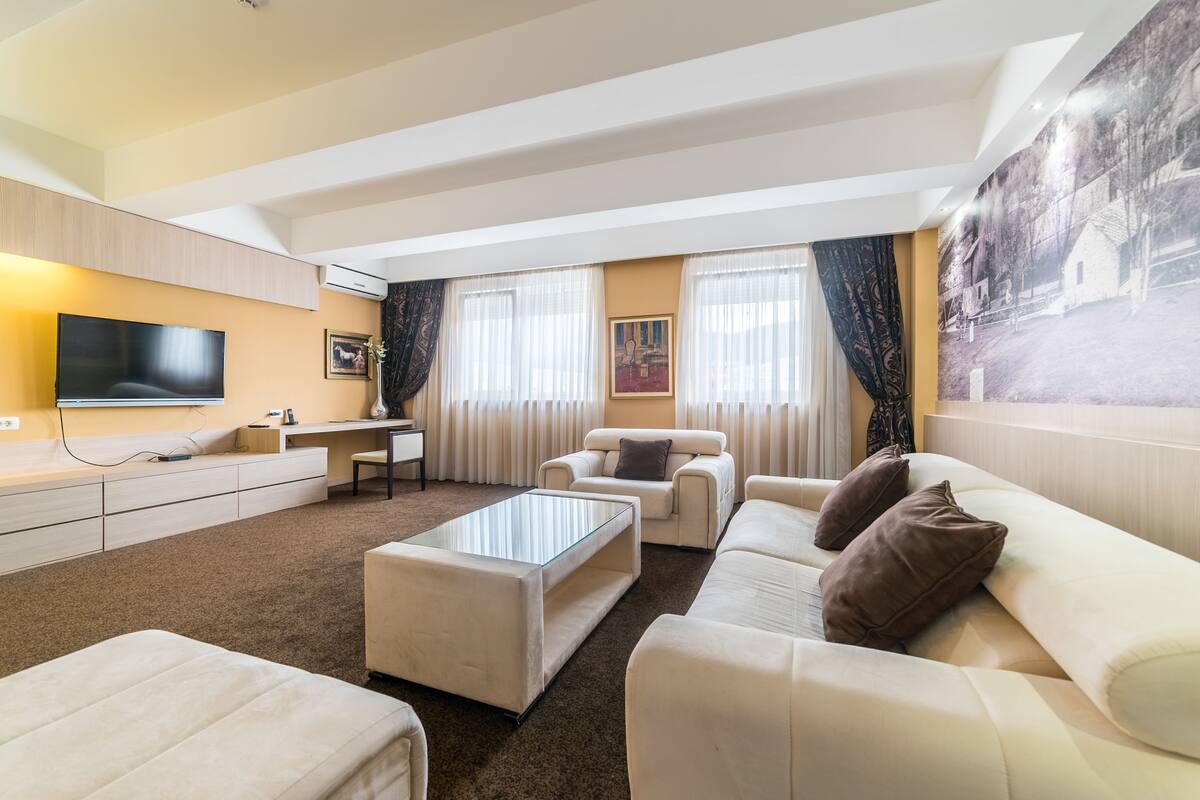 Ein modernes Wohnzimmer mit Flachbildfernseher, Sofa, Couchtisch und Schreibtisch.