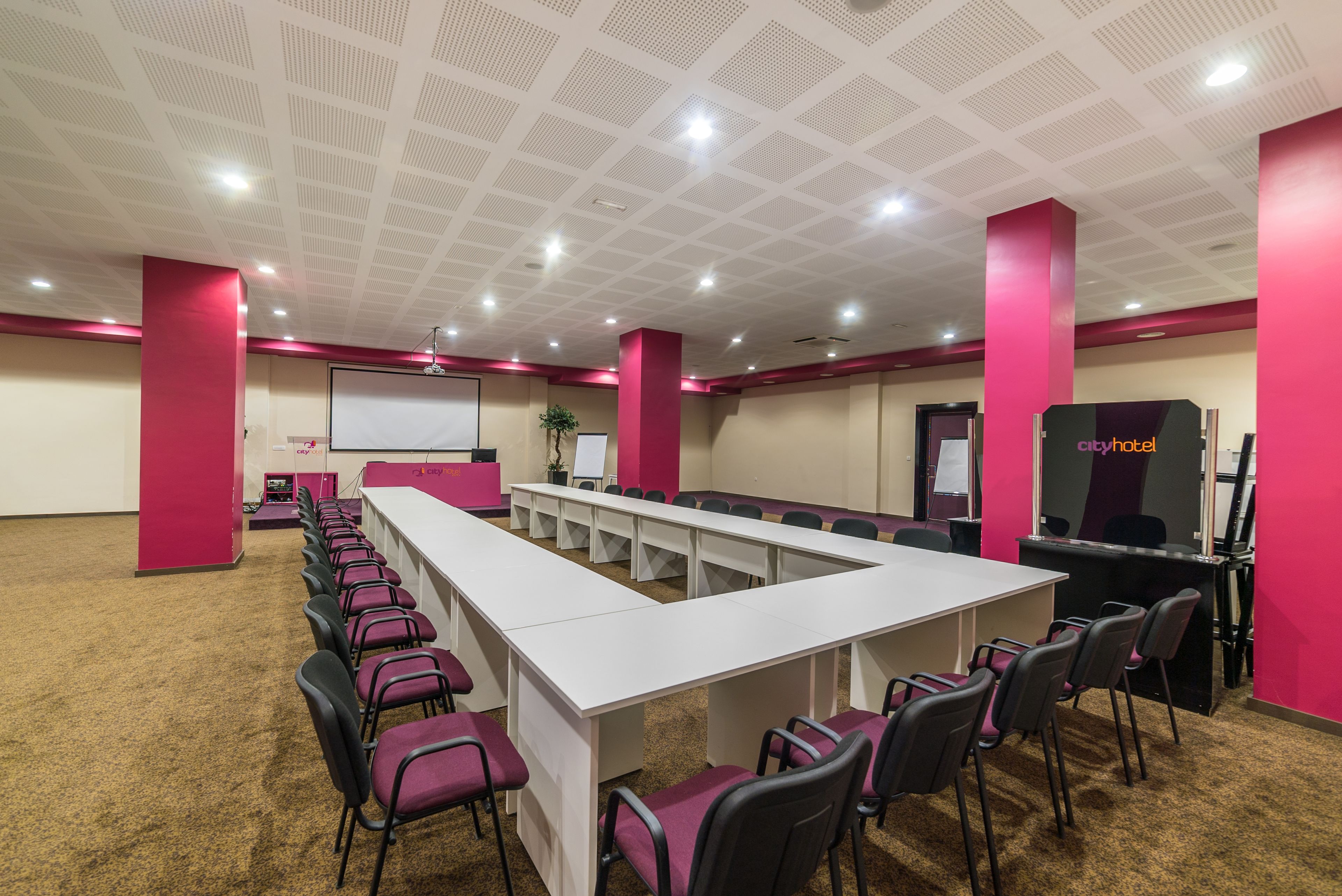 Un salón de conferencias con una larga mesa, sillas y una pizarra.