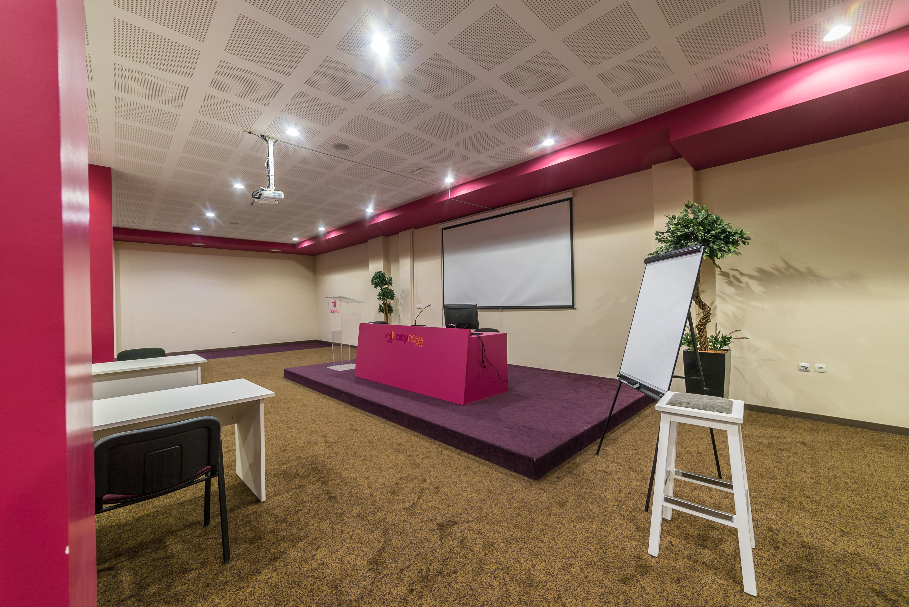 A conference room with a whiteboard, a podium, and a projector.
