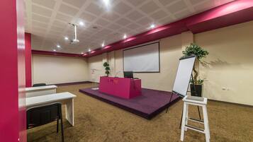 A conference room with a whiteboard, a podium, and a projector.