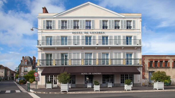 Een gebouw met twee verdiepingen, met een bord met de tekst 'HOTEL DE LONDRES' op de gevel.