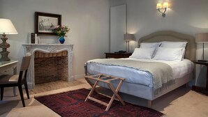 Een slaapkamer met een bed, nachtkastjes, een open haard, een stoel en een vloerkleed.