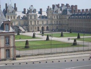 A large, historic building with symmetrical architecture, a central courtyard with trimmed hedges, and a paved walkway. - Hôtel de Londres (Fontainebleau)