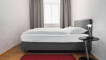 Un dormitorio moderno con una cama, una mesita de noche y una ventana con cortinas.