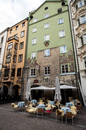 A row of outdoor cafe tables with umbrellas, set against a backdrop of colorful historic buildings. - Golden Roof Apartments by Penz (Innsbruck)