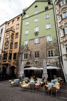 Eine Reihe von Terrassentischen mit Sonnenschirmen vor dem Hintergrund bunter historischer Gebäude.