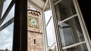 Vista a través de una ventana con un reloj en un edificio.